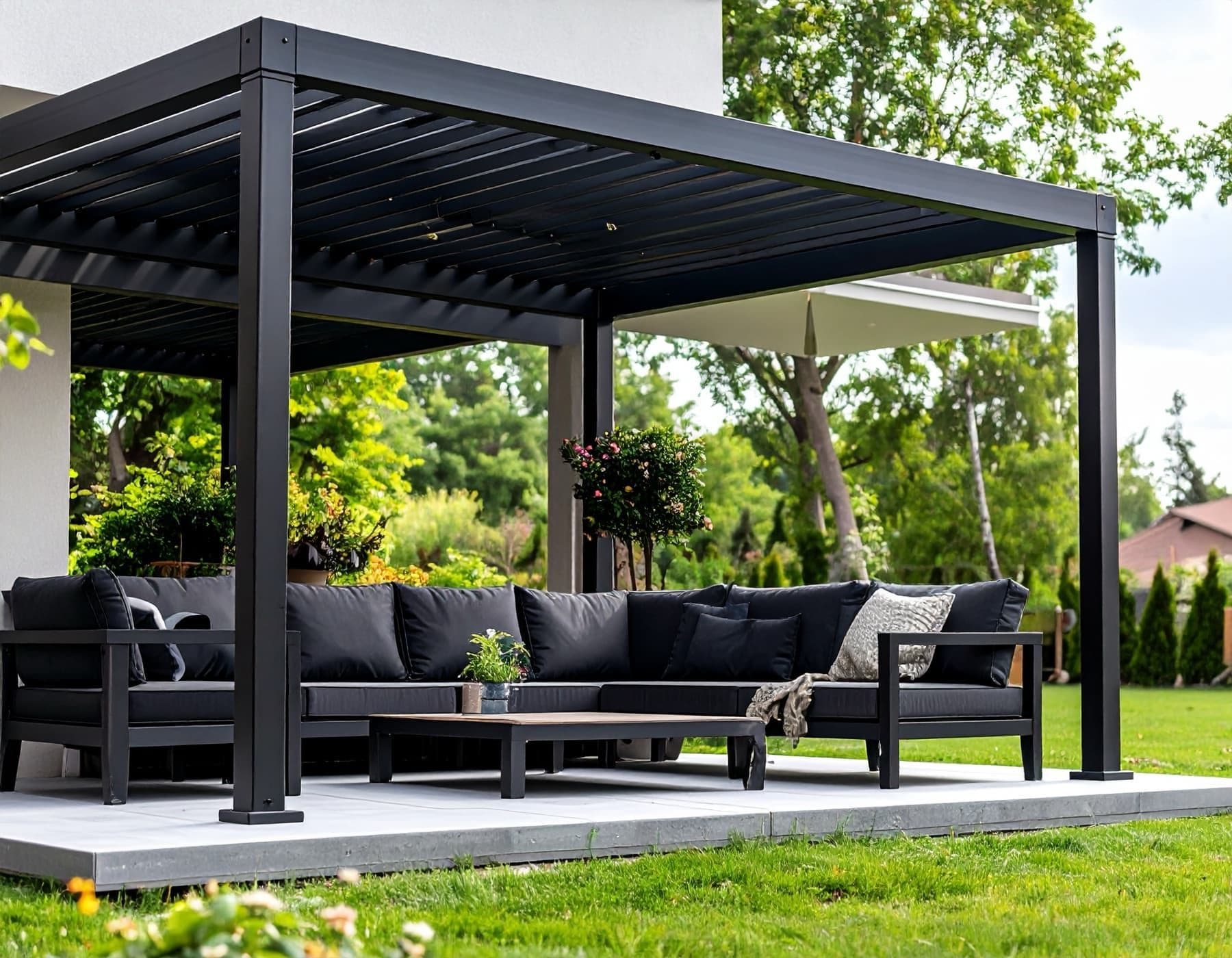 Svart pergola med loungegrupp i en grönskande trädgård